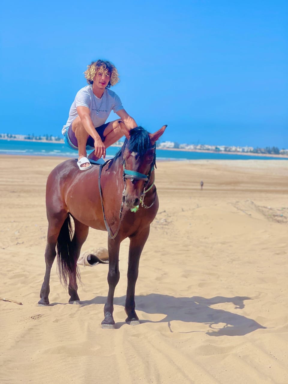 Mokhtar crouching on Assif's back on the beach