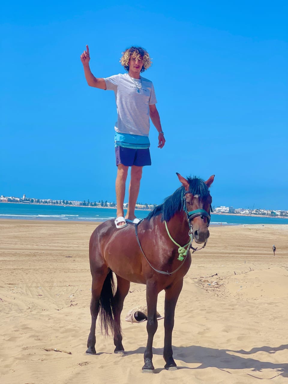 Mokhtar standing on Assif's back with Essaouira in the background